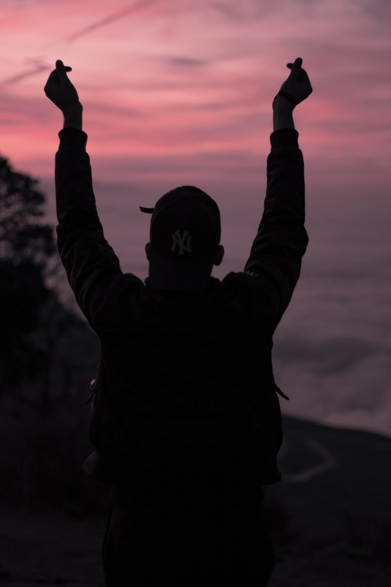 silhouette of man raising his hands